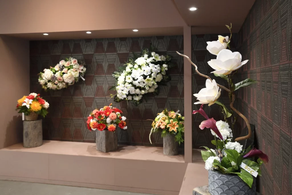 Mur d'exposition présentant diverses compositions de fleurs synthétiques pour funérailles.