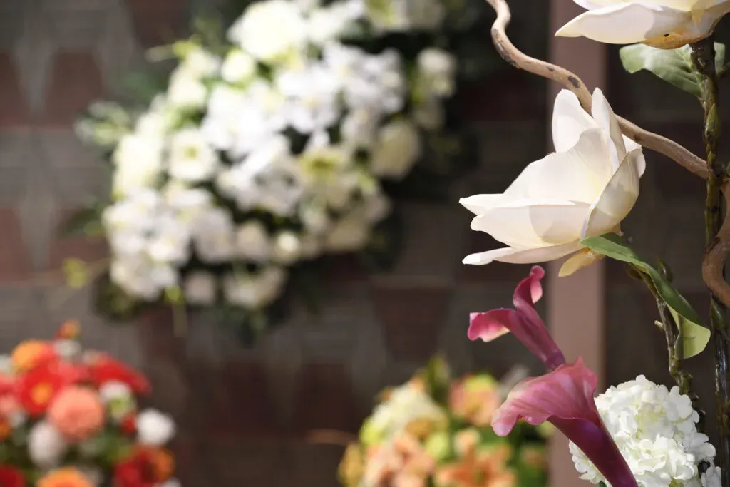 Magnifique composition de fleurs artificielles blanches et bordeaux pour deuil.